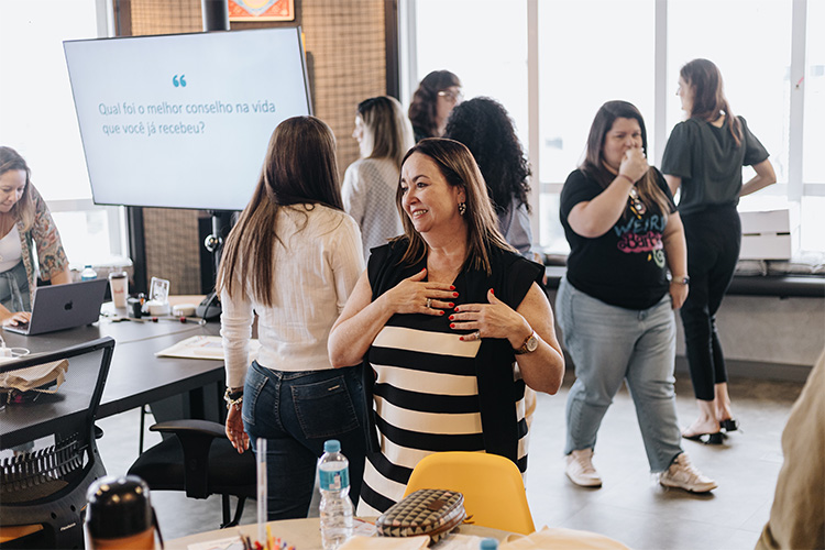 Mulheres participantes do treinamento em pé e andando pela sala em uma das atividades de aula.