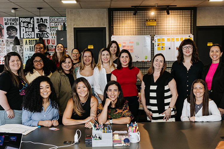 Todas as mulheres que participaram do evento estão posicionadas em direção a foto. Algumas estão de pé enquanto outras estão sentadas na frente das demais.